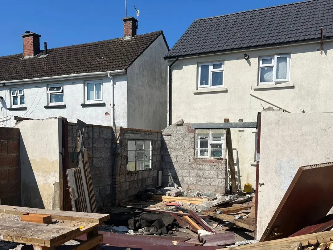 Garage mid-demolition with timber, rubble and roof sheets across the yard
