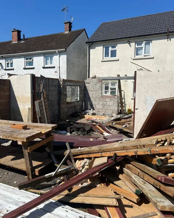 Garage mid-demolition with timber and rubble stacked across the yard